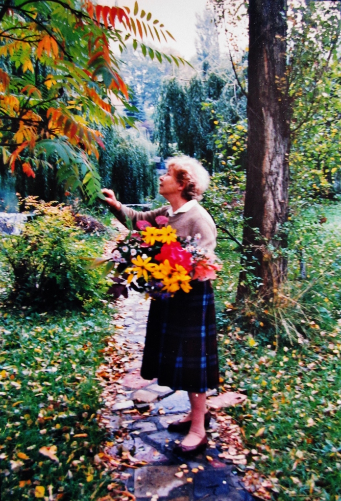 My grandmother gathering flowers in her garden.